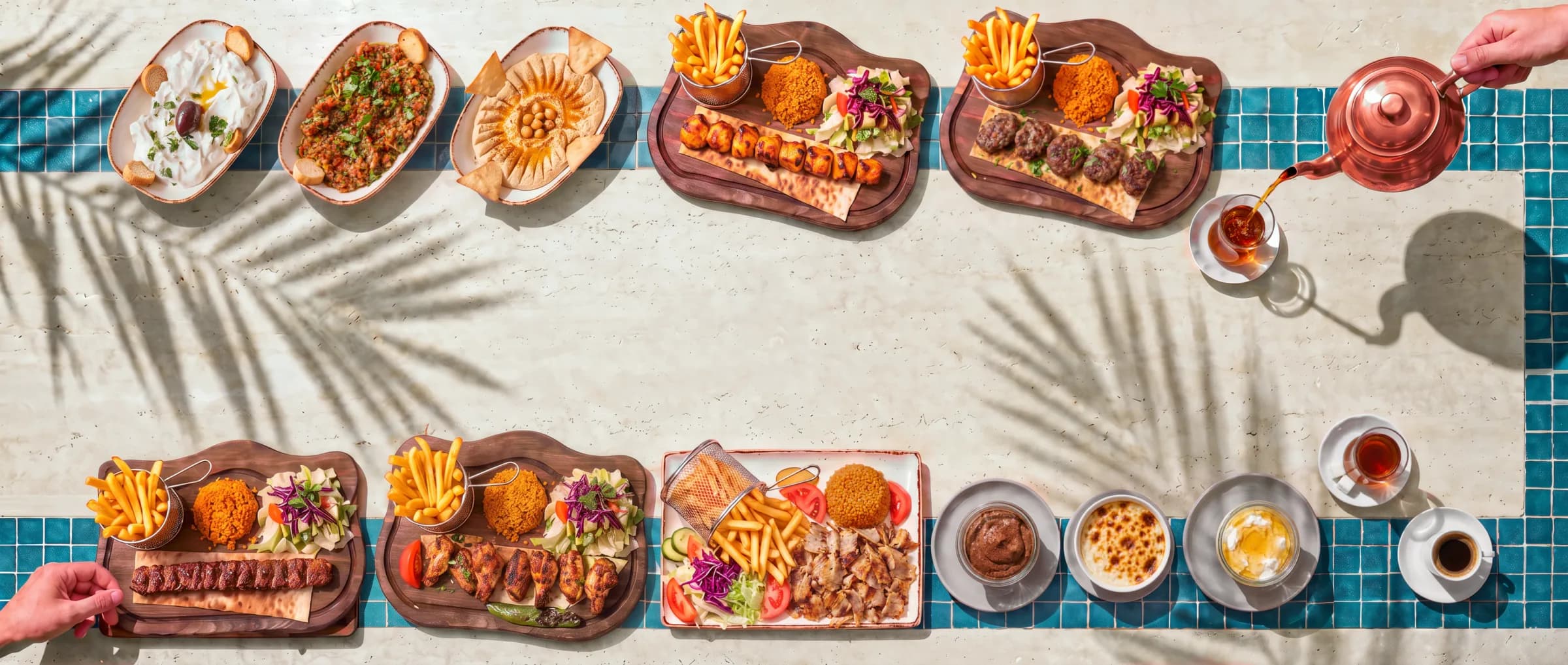 La Tablée du midi : les douze plats du menu déjeuner sur le travertin crème au soleil, entre deux bandes de zellige, et une main qui verse le thé de la théière en cuivre.